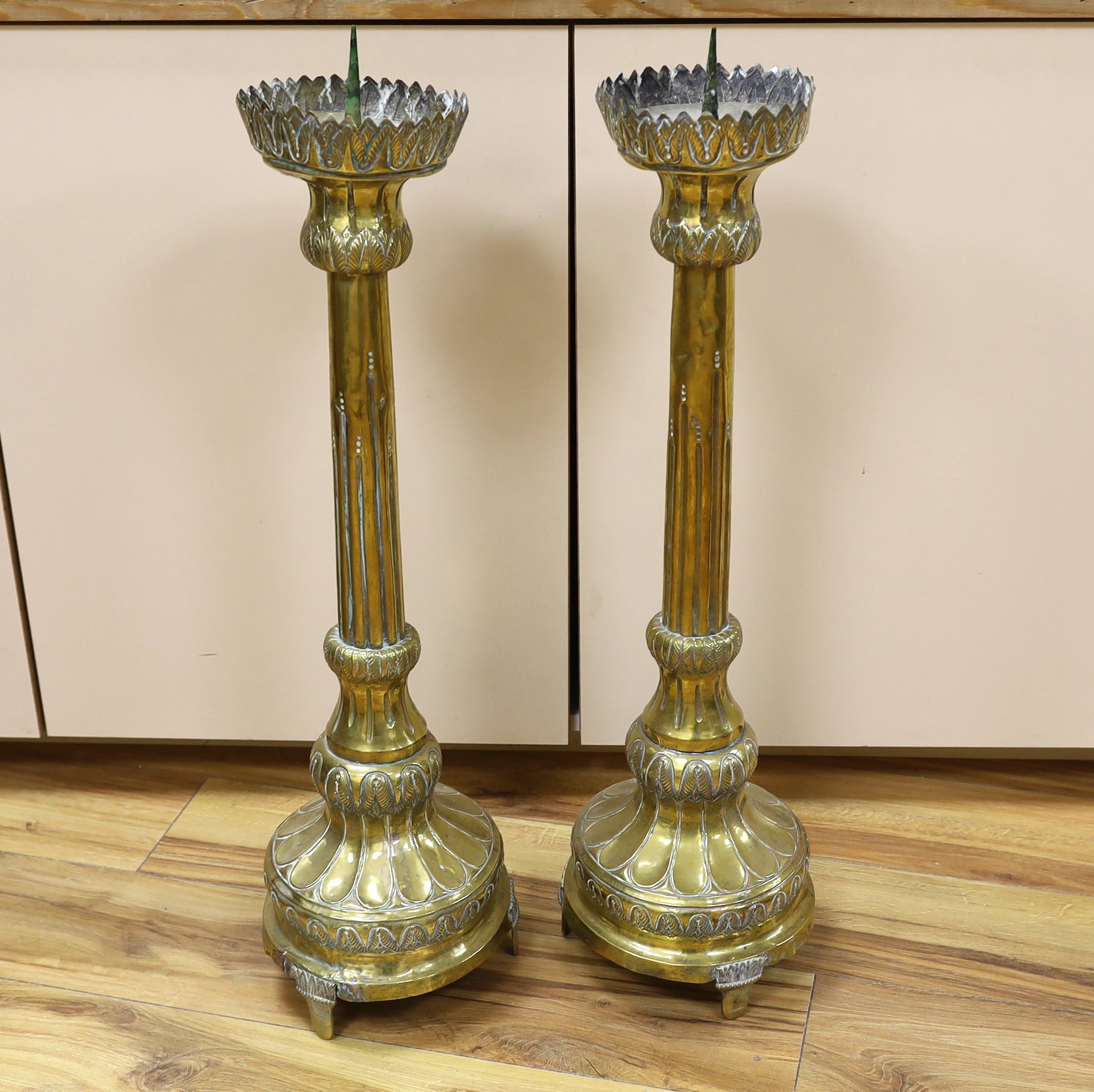 A pair of tall 19th century repoussé brass pricket altar sticks, 76cm high